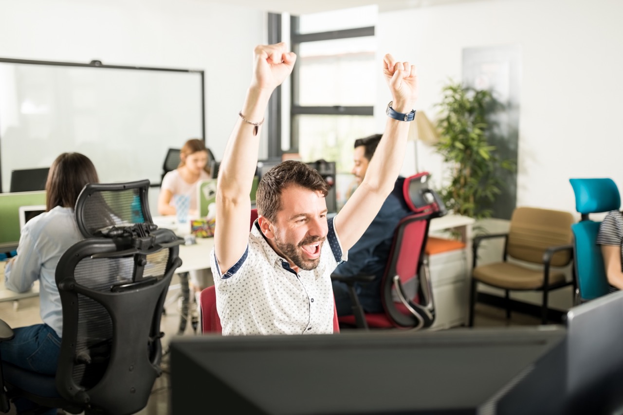 portrait-cheerful-positive-man-causal-outfit-raising-hands-celebrating-achievement-sitting-modern-office-with-colleagues-background Large.jpeg