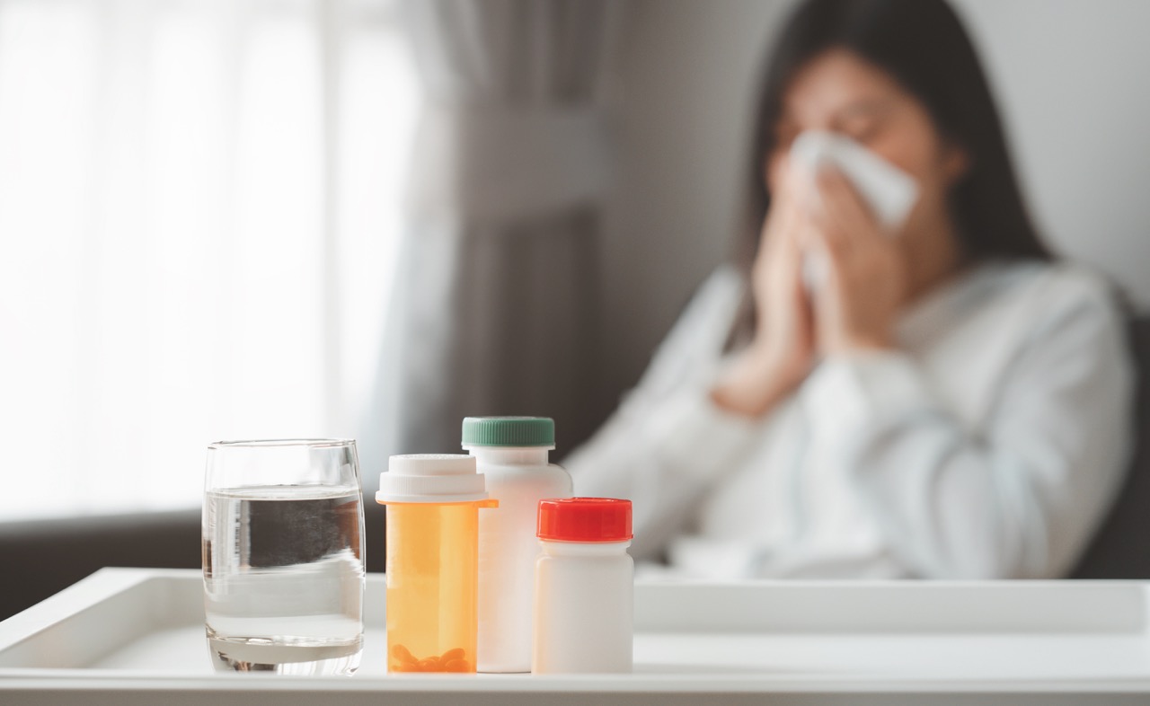 vecteezy_medicines-and-glass-of-water-with-sick-woman-in-background_1252057 Large.jpeg